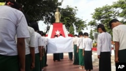 FILE - Students bow before a statue of Myanmar national hero Gen. Aung San during a ceremony in Naypyitaw, Myanmar, July 19, 2017.