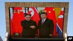 Una pantalla gigante de TV muestra la reunión entre el líde de Corea del Norte, Kim Jong Un y el presidente de China, Xi Jinping en el Gran Salón del Pueblo en Beijing el martes, 19 de junio de 2018.