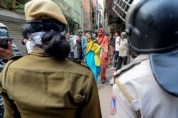 FILE - A Muslim woman (C) shouts at security personnel that patrol on the streets in Shaheen Bagh area after removing demonstrators continuously protesting against a new citizenship law, March 24, 2020.