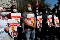 FILE - People hold pictures of Saudi journalist Jamal Khashoggi during a gathering to mark the second anniversary of his killing at the Saudi Consulate, in Istanbul, Turkey, Oct. 2, 2020.