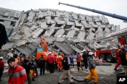 FILE - Rescue workers search a collapsed building from an early morning earthquake in Tainan, Taiwan, Feb. 6, 2016.