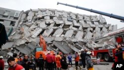 Rescue workers search a collapsed building from an early morning earthquake in Tainan, Taiwan, Feb. 6, 2016. 