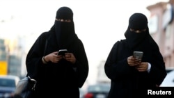 FILE - Saudi women use the Careem app on their mobile phones in Riyadh, Saudi Arabia, Jan. 2, 2017.Saudi Arabia is well known as the world's most gender-segregated nation, where women live under the supervision of a male guardian, cannot drive, and in public must wear head-to-toe black garments.