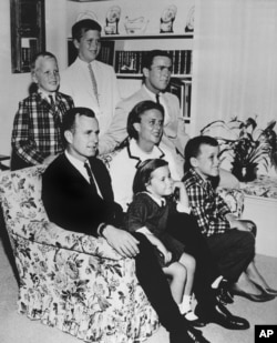 FILE - In this 1964 file photo, George H.W. Bush sits on couch with his wife Barbara and their children. George W. Bush sits at right behind his mother. Behind couch are Neil and Jeb Bush.