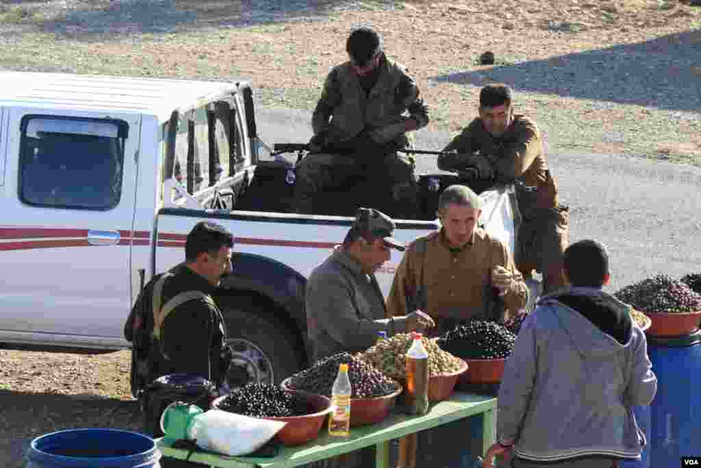 Peshmerga soldiers taste olives for sale outside Bashiqa, Iraq on Nov. 23, 2016. (H.Murdock/VOA)