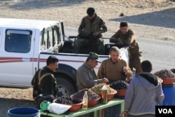 Peshmerga soldiers taste olives for sale outside Bashiqa, Iraq on Nov. 23, 2016. (H.Murdock/VOA)