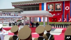 Russian President Vladimir Putin, rear left, and North Korea's leader Kim Jong Un, both are on the podium, attend the official welcome ceremony at the Kim Il Sung Square in Pyongyang, North Korea, June 19, 2024.