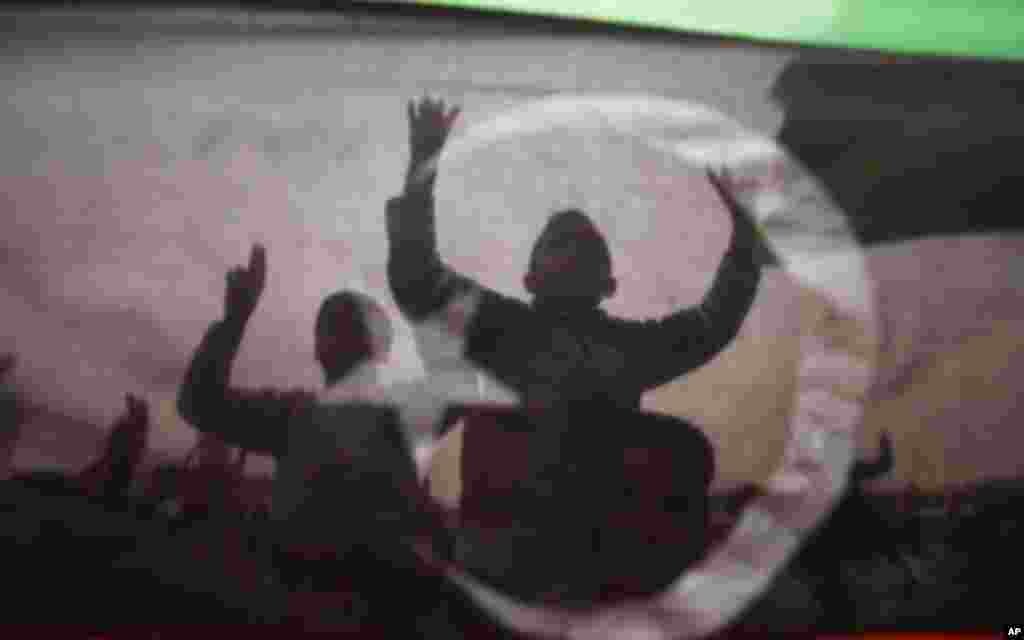 Protesters are seen through a Kingdom of Libya flag during celebrations after a U.N. resolution authorising a "no-fly" zone and military attacks on Muammar Gaddafi's forces, in Tobruk, east of Tripoli, March 18, 2011. REUTERS/Suhaib Salem (LIBYA - Tags: P