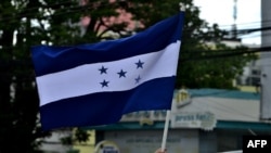 Un hombre sostiene la bandera nacional de Honduras mientras participa en una caravana por el Boulevard Morazán, el 15 de julio de 2020. 