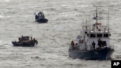韩国海岸警卫队的船只（右）拖着一艘越界的朝鲜木渔船（左下）先北边海域驶去。（2011年3月27日）