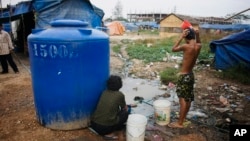 FILE PHOTO - A Cambodian bathes near his slum home Thursday, Feb. 19, 2009, on the outskirts of Phnom Penh, Cambodia. (AP Photo/David Longstreath)