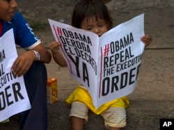 FILE – A child holds a bilingual leaflet calling for the U.S. repeal of sanctions against Venezuela, in Caracas, April 10, 2015.