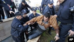 Algerian policemen detain a protester during a demonstration in Algiers, February 12, 2011