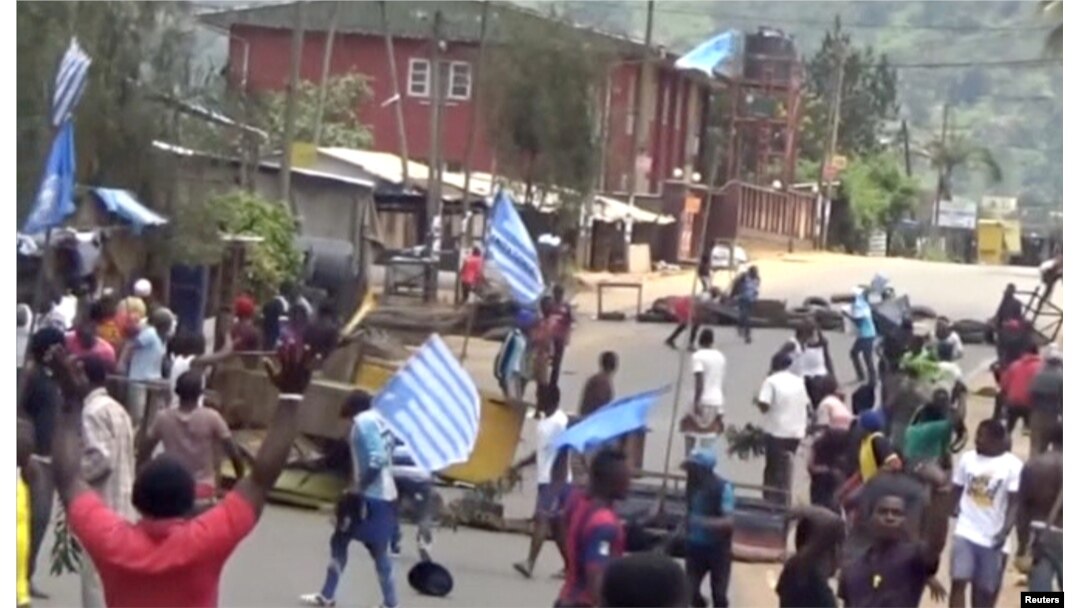 FILE - A still image taken from a video shot on Oct. 1, 2017, shows protesters waving Ambazonian flags in front of road block in the English-speaking city of Bamenda, Cameroon.