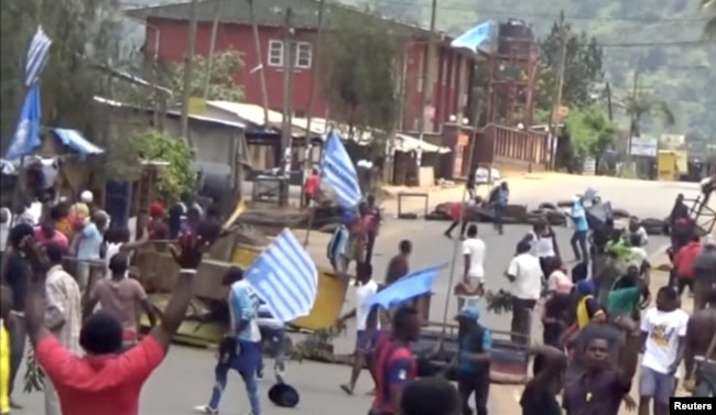 FILE - A still image taken from a video shot on Oct. 1, 2017, shows protesters waving Ambazonian flags in front of road block in the English-speaking city of Bamenda, Cameroon.