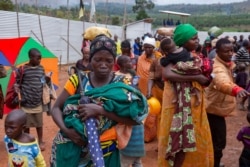 Nzeyimana Consolate, center, carries her baby as she arrives at the Nyabitara Transit site in Ruyigi, Burundi, Oct. 3, 2019.
