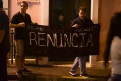 Citizens carrying a banner that reads in Spanish "Ricarod Rosello, renounce" protest near the executive mansion denouncing a wave of arrests for corruption that has shaken the country and demanding he resign, in San Juan, Puerto Rico, July 11, 2019.…
