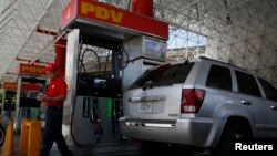 A worker walks next to a fuel dispenser at a gas station, in Caracas, Venezuela, Aug. 29, 2014.