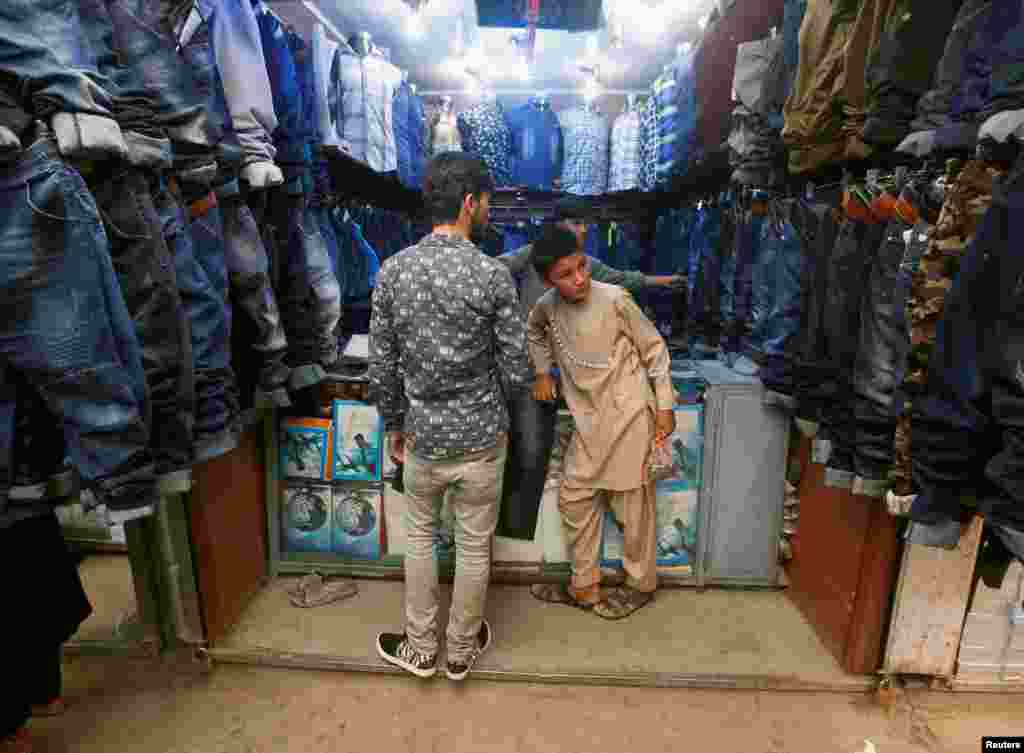 یک جوان در حال خرید لباس عید در یکی از فروشگاه های شهر کابل.