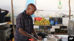 In this photo taken, Tuesday May, 22, 2012 Ahmed Jama chops meat and vegetable at one of his restaurants in Mogadishu, Somalia.