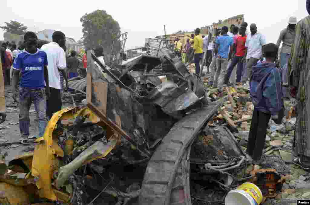 Mutane sunyi dafifi kewaye da inda daya daga cikin boma-boman ya tashi domin ganewa idanusu a Ajilari-Gomari kusa da filin jirgin sama na Maiduguri a ranar 2 ga watan Maris 2014.