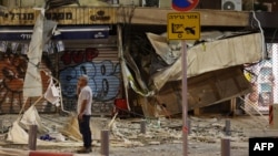 Seorang pria berdiri di depan sebuah toko yang rusak di Tel Aviv, setelah terkena roket yang ditembakkan militan Palestina dari Jalur Gaza hari Sabtu, 7 Oktober 2023.