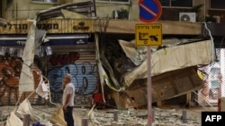 Seorang pria berdiri di depan sebuah bangunan toko yang hancur akibat serangan roket Hamas, di Tel Aviv, pada 7 Oktober 2023. (Foto: AFP/Jack Guez)