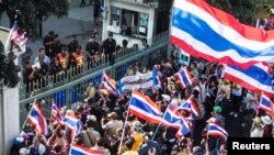 Para demonstran anti-pemerintah berdiri di gerbang kantor bea cukai di Bangkok (14/1). (Reuters/Nir Elias)