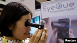 Phoebe Yu mendemonstrasikan cara kerja alat "VisionCheck 2" dari EyeQue (Foto: REUTERS/Rick Wilking). 