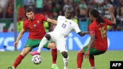 Le milieu de terrain français N'Golo Kanté au centre aux prises avec le défenseur portugais Ruben Dias (g) et le milieu de terrain portugais Renato Sanches lors du match de football de l'Euro 2020 entre le Portugal et la France à Budapest le 23 juin 2021.