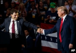 12th Congressional District Republican candidate Troy Balderson (L) reaches for President Donald Trump as he speaks at a rally at Olentangy Orange High School in Lewis Center, Ohio, Aug. 4, 2018.