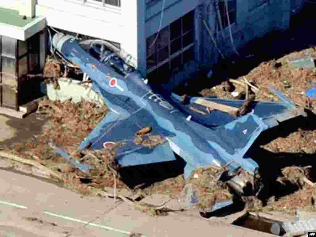 A Japan Self Defense Forces fighter jet is swept into a building by a tsunami at an airbase in Higashimatsushima City, Miyagi Prefecture in northeastern Japan March 12, 2011.
