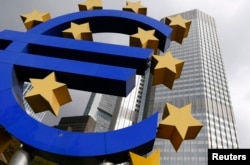 The euro logo sculpture is seen in front the headquarters of the European Central Bank in Frankfurt, Oct. 26, 2014.