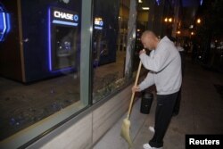 A man sweeps up broken glass after a riot swept through the area in protest to the election of Republican Donald Trump as President of the United States in Portland, Oregon, U.S., Nov. 10, 2016.