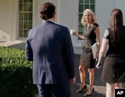 FILE - Counselor to the President Kellyanne Conway, center, waits for White House communications director Anthony Scaramucci, left, outside the West Wing of the White House in Washington, July 26, 2017.
