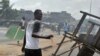 Un homme tient une machette alors que des habitants en colère brûlent des pneus et bloquent la rue pendant des manifestations qui avaient tué au moins six femmes, le 3 mars 2011 à Abobo, un quartier ouvrier de Abidjan. PHOTO AFP / ISSOUF SANOGO (Photo par ISSOUF SANOGO / AFP)