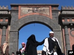 A woman walks past a fortified gate in Sanaa