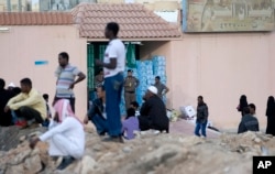 FILE - Saudi security forces watch Ethiopians gather as they wait to be repatriated in Manfouha, southern Riyadh, Nov. 13, 2013.