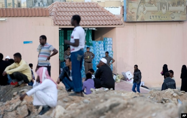 FILE - Saudi security forces watch Ethiopians gather as they wait to be repatriated in Manfouha, southern Riyadh, Nov. 13, 2013.