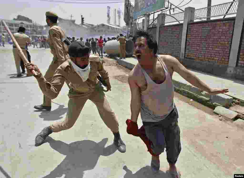 An Indian policeman uses a baton to disperse a protest during a demonstration in Srinagar. Indian police detained dozens of protesting government employees in Srinagar as they attempted to reach the civil secretariat, which houses the office of Kashmir&#39;s chief minister and his colleagues, to demand their long pending arrears and a regularization of temporary jobs, according to protesters.