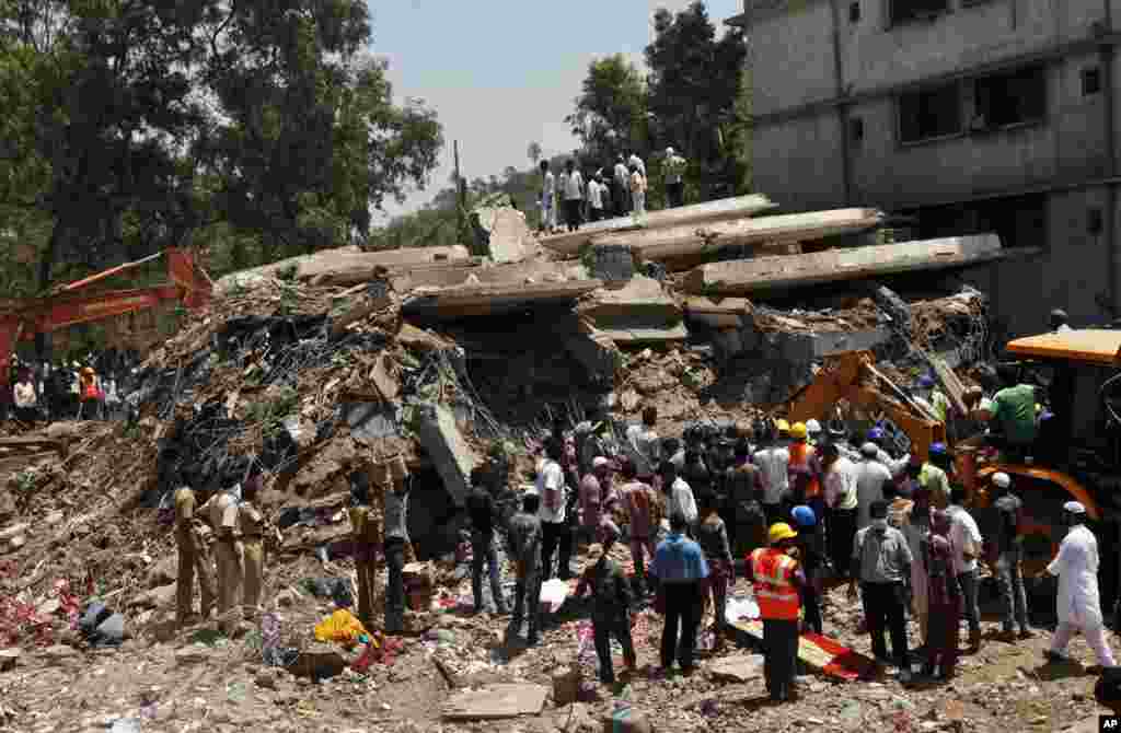 People gather around a collapsed building as a rescue operation continues on the outskirts of Mumbai, India, April 5, 2013.