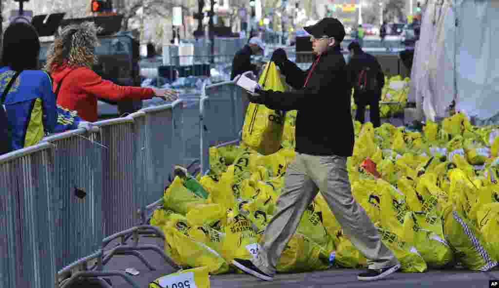 Seorang petugas mengembalikan tas berisi barang-barang seorang pelari dekat garis finish di Marathon Boston, setelah pemboman menewaskan tiga orang dan melukai lebih dari 170 orang di Boston (16/4).