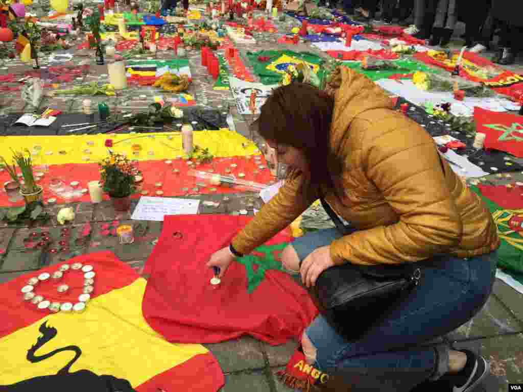 Woman places candle on Moroccan flag at makeshift memorial for terror bombing victims in Brussels, Belgium, March 23, 2016. (N. Pourebrahim / VOA)