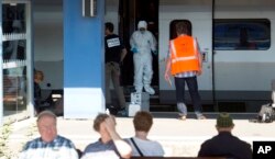 People wait for a train in the foreground as members of a police forensics team take part in an investigation next to a Thalys train on the platform at Arras train station, northern France, Aug. 22, 2015.