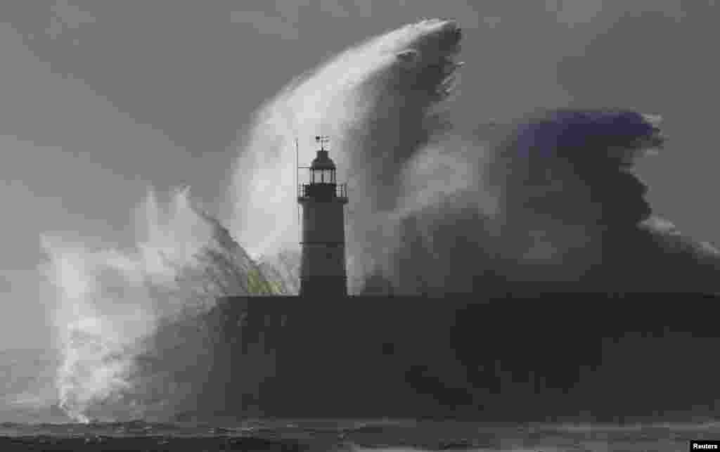Waves crash against a lighthouse during storms that battered Britain and where a 14-year-old boy was swept away to sea at Newhaven in South East England, Oct. 28, 2013. 