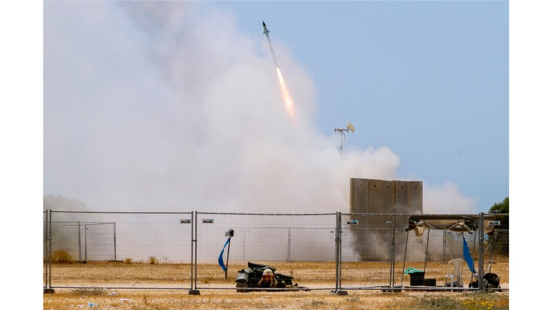 Seorang tentara Israel berlindung saat rudal dari sistem anti-pesawat Iron Dome lepas landas untuk mencegat roket dari Jalur Gaza di Ashkelon, Israel selatan, Selasa, 11 Mei 2021. (AP Photo / Ariel Schalit)