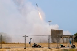 Seorang tentara Israel berlindung saat rudal dari sistem anti-pesawat Iron Dome lepas landas untuk mencegat roket dari Jalur Gaza di Ashkelon, Israel selatan, Selasa, 11 Mei 2021. (AP Photo / Ariel Schalit)