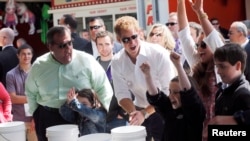 Britain's Prince Harry and New Jersey Governor Chris Christie (L) react as Taylor Cirigliano, 11, of Middletown wins a prize playing the Ball Toss game on the boardwalk in Seaside Heights, May 14, 2013.