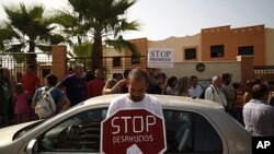 A demonstrator holds a sign that reads "Stop evictions," outside a townhouse during a protest to stop the eviction of a family in Torre del Mar, near Malaga southern Spain, June 29, 2011