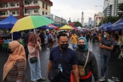 Para pengunjung mengenakan masker saat berbelanja makanan untuk berbuka puasa di pasar Ramadhan, di tengah pandemi COVID-19, di Kuala Lumpur, Malaysia, 15 April 2021. (REUTERS / Lim Huey Teng)